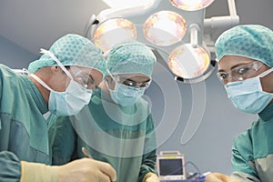 Three Surgeons At Work In Operating Theatre