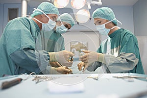 Three Surgeons At Work In Operating Theatre