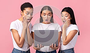 Three Surprised Girls Looking At Laptop Browsing Internet, Studio Shot