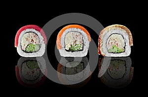 Three sushi rolls with salmon, tuna and eel on black background