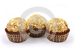 Three sweet chocolate bonbons in golden foil
