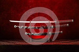 Three swords on stand, katana blade exposed, red