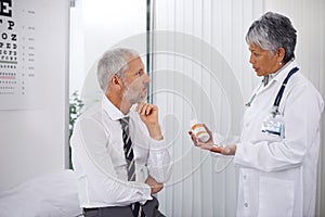 Three tablets, twice a day. A mature doctor giving a bottle of pills to one of her patients during a checkup.