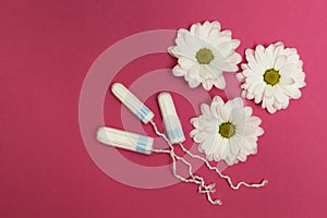 Three tampons on a pink background with white flowers