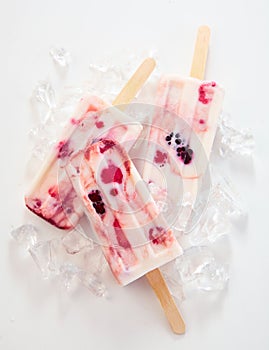 Three tasty frozen yogurt and berry popsicles