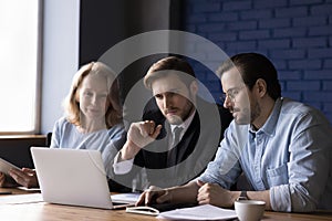 Three teammates working together use laptop in office