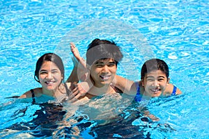 Three teen siblings smiling together in pool photo