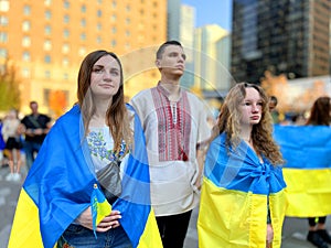 Three teenagers are hiding behind flags in Ukrainian embroidered national clothes They are waiting for the end of the