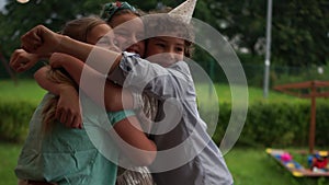 Three teenagers hugging at a birthday party. The birthday boy is making a birthday boy's hat, happy childhood