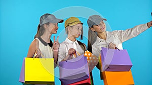 Three teenagers make selfies with colorful packages. Blue background