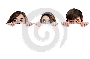 Three teenagers peeking over a white background