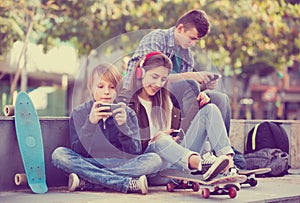 Three teenagers with phones outdoors