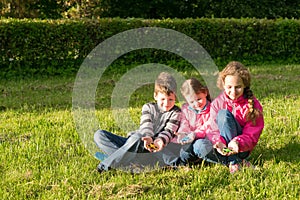 Three teenagers sitting enjoying on the grass playing in spinner