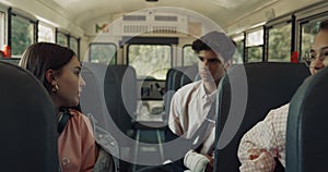 Three teenagers sitting school bus talking alone. Smiling girl taking seat.