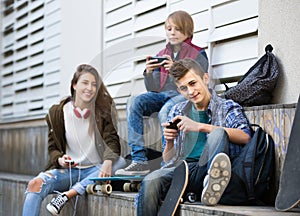 Three teenagers with smartphones in outdoors