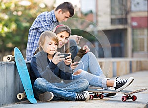 Three teenagers with smartphones in outdoors