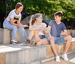 Three teenagers with smartphones are talking about play on walk