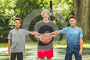 three teens friends in sportswear playing basketball game