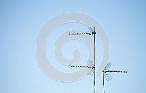 Three television antennas for analog and digital terrestrial television installed on mast on a roof in Spain, with grill and