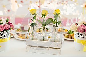 Three tellow roses in glass vasen on fancy decorated table