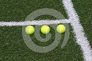 Three tennis balls on green court