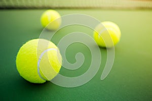 Three tennis balls on green hard court