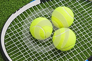 Three tennis balls lie on a tennis racket strings. over green la