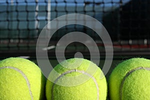 Three Tennis balls with the net in background