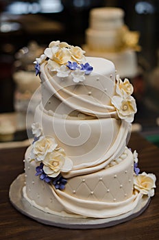 Three tier champagne colored wedding cake with yellow and purple flowers