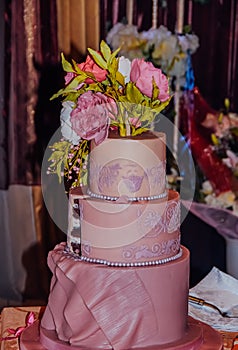 Three-tier pink wedding cake decorated with mastic peonies. Wedding Concept
