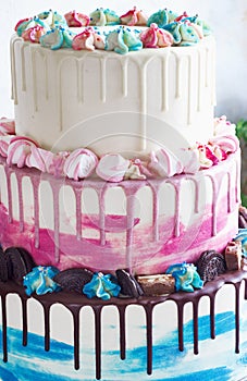 Three-tiered colored cake with colored smudges of chocolate on a light background. Picture for a menu or a confectionery catalog,