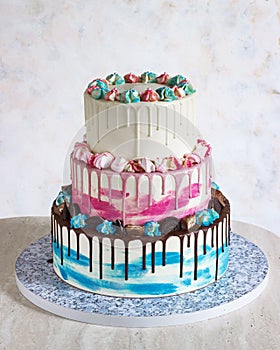 Three-tiered colored cake with colored smudges of chocolate on a light background. Picture for a menu or a confectionery catalog,