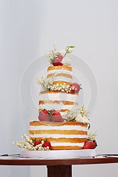 Three-tiered wedding cake with strawberries on table