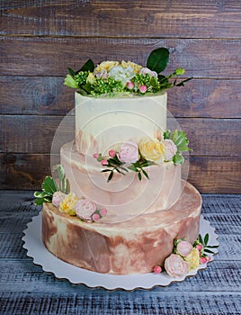 Three-tiered wedding ombre cake decorated with roses and greener