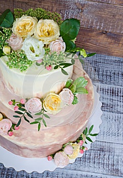 Three-tiered wedding ombre cake decorated with roses and greener