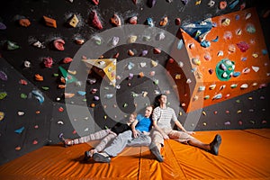 Three tired climbers on the mat near rock wall indoors