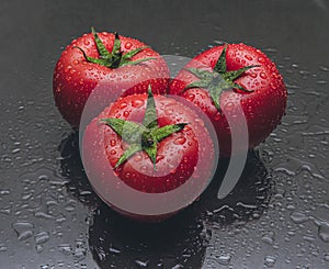 Three tomatoes on black background