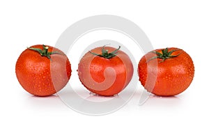 Three tomatoes in water droplets on white