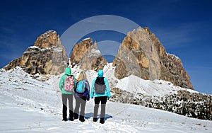 Three tourists looking at the beautiful mountain group Sassolungo Langkofel. photo