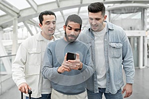 Three Tourists Men Using Cellphone Booking Travel Tickets In Airport