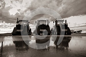 Three tractors lined up in sepia tone