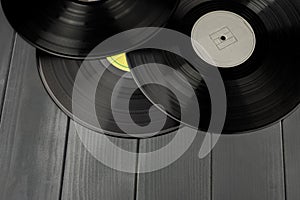 Three traditional glossy black vinyl records without scratches on a gray wooden table