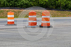 Three traffic barrels in a road construction area, orange safety barricade, asphalt copy space