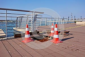 Three traffic cones standing on boundary of open hatch