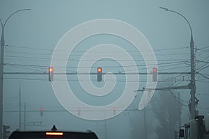 three traffic lights in the fog hang over the road