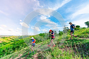 Three trail runners, a woman and an Asian man. Wearing runners, sportswear, practicing running on a dirt path in a high mountain