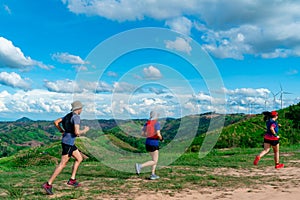 Three trail runners, a woman and an Asian man. Wearing runners, sportswear, practicing running on a dirt path in a high mountain