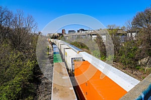 Three trains riding on the railroad tracks surrounded by lush green trees and bare winter trees and clear blue sky in Atlanta