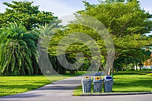 Three trashcans in a park with green tree and plants background