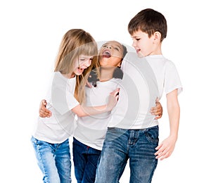 Three trendy children with different complexion laugh and embrace each other